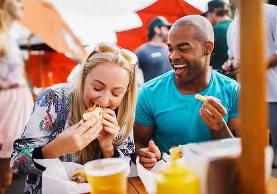 Two smiling friends enjoying meal outside