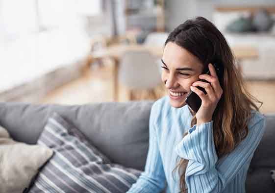 Woman smiling while talking on phone on couch