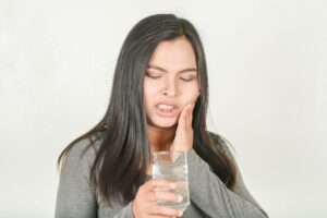 Woman with sensitive teeth drinking ice water