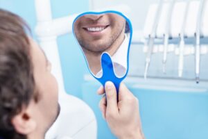 dental patient smiling in mirror after full mouth reconstruction