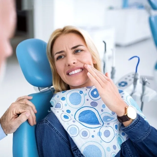 Woman holding her cheek in pain before same-day emergency dentistry in Plano, TX